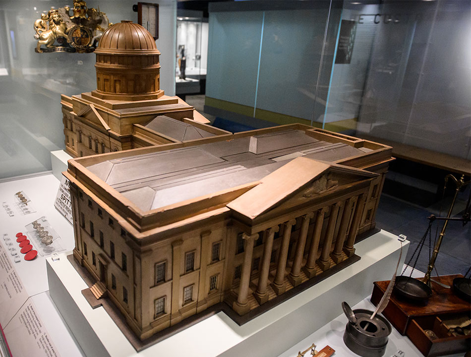 Wooden model of a large building with columns at the entrance and a large dome, in museum display