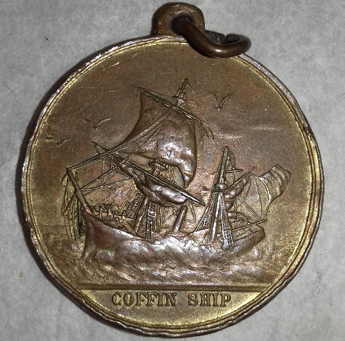 Bronze medallion showing a 19th century sailing ship in trouble in rough seas over the words 'COFFIN SHIP'