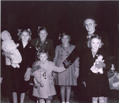 Black and white image of school children clutching dolls 