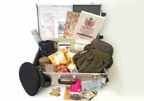 A suitcase containing objects associated with the Army such as a kit bag, documents and Army Dress cap