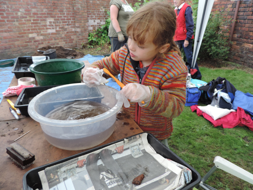Young archaeologist washes finds on site in Rainford