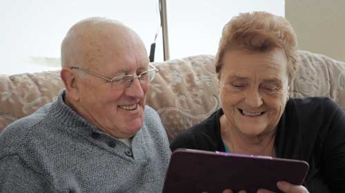 A smiling gentleman and lady looking at a tablet