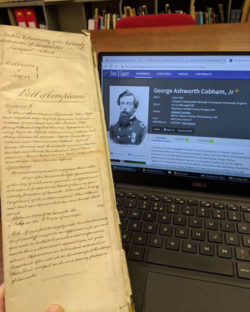 document next to computer screen showing info on George Ashworth Cobham Jr