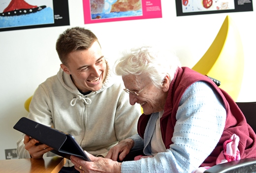 A man and elderly lady smiling looking at app 