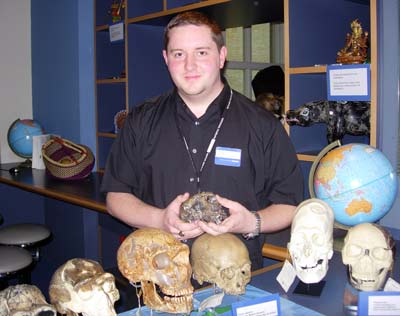 a smiling man in a blue shirt surrounded skulls