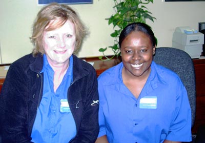 Photo of two smiling women in blue shirts and staff badges 