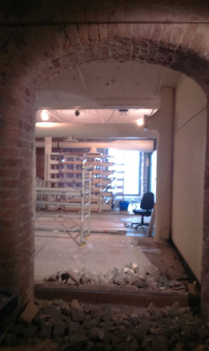 old arched doorway into empty room with some rubble on the floor