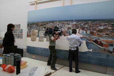 Man being filmed painting a large picture