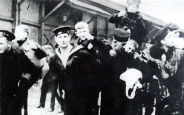 Black and white photo of boys being carried by sailors
