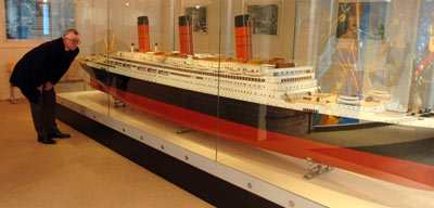 photo of a man looking at a large ship model in a case