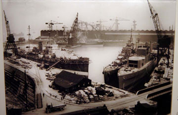 archive photo of several large ships in a dock surrounded by cranes