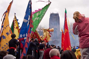 Liverpool's Anglican Cathedral seen in the distance, with crowds and colourful Chinese New Year flags in the foreground