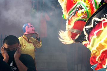 Chinese New Year photograph with colourful Chinese dragon on the right and men wreathed in smoke on the left