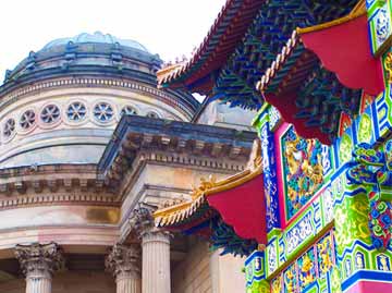 19th-century stone building with Corinthian columns and dome beside a colourful Chinese arch