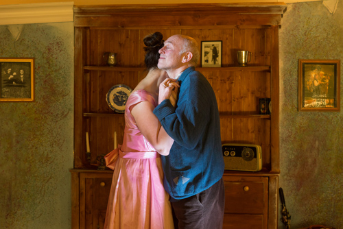 A lady in a pink dress and a gentleman in a blue jumper slow dancing