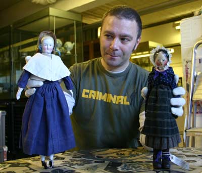 Curator holding 2 old dolls