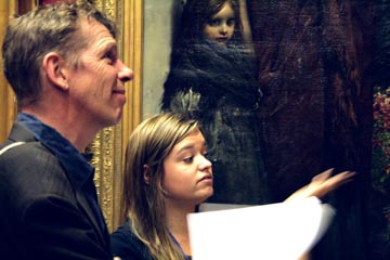 Man and a woman looking at a painting of a child
