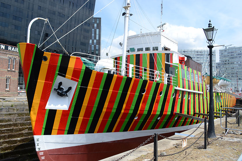 ship painted in bold stripes of yellow, red, green and black
