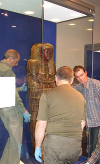 people installaing an Egyptian coffin in a display case