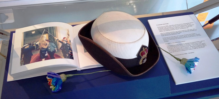 Navy uniform hat, paper flowers and wedding photo in museum display case