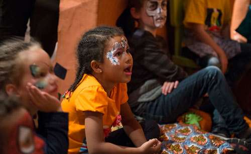 children with their faces painted, listening intently to an unseen storyteller