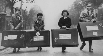 archive photo of 4 young children carrying suitcases