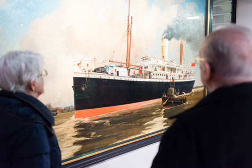 visitors looking at the large ship painting