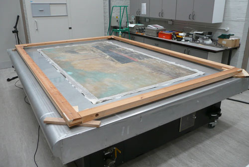 large painting lying flat on a table with a protective cover