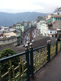View down to a pedestrianised street with shops on either side and mountains in the background