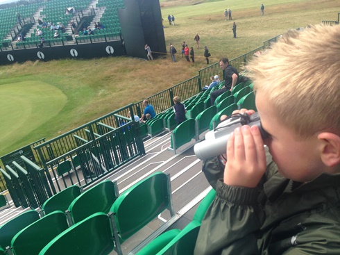 young child with binoculars looking at golf green
