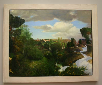 Landscape painting in a pine frame hanging on a gallery wall