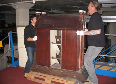 Two men lifting a large model house