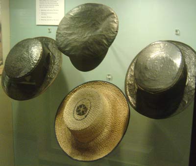 a display of 4 boater hats, 3 covered in tar