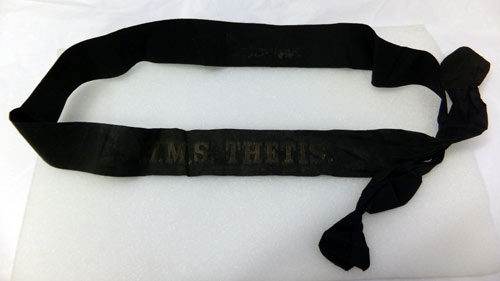black band or ribbon with faded gold lettering 'HMS Thetis'