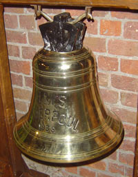 a shiny gold bell, suspended from a wooden support