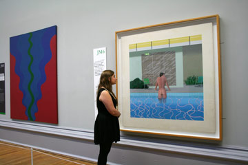 Young woman looks at paining on a gallery wall