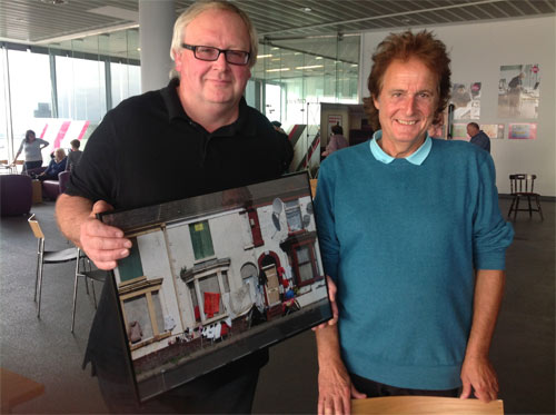 two men, one holding a framed photograph