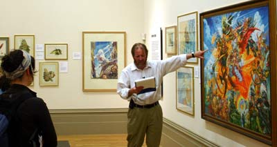 man pointing at a painting while reading from a clipboard