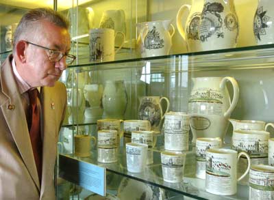 photo of a man looking into a glass case of cream coloured jugs