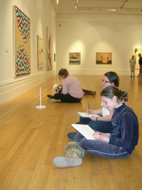 Two girls sitting on the floor of a gallery with drawing materials