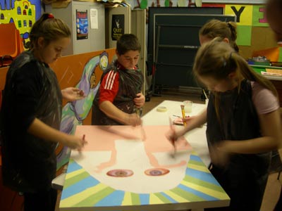 A group of children painting on one canvas