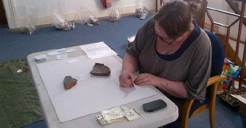 archaeologist documenting objects from an excavation