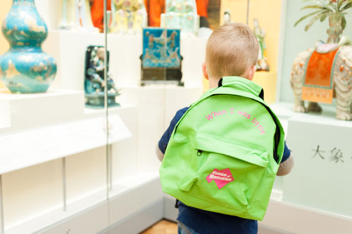 young boy with a backpack looking at art gallery displays