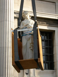 marble sculpture in a wooden box being lifted suspended from a crane