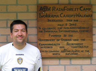 Smiling man in football shirt in front a wooden sign