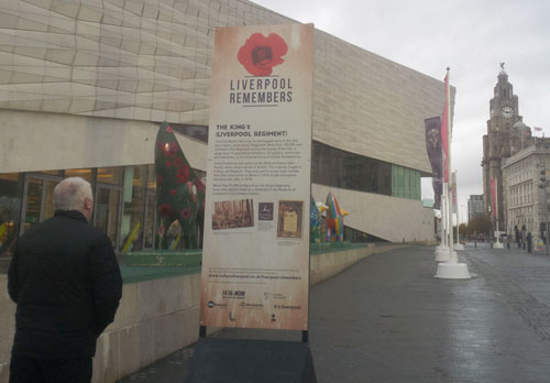 man looking at a large sign with a poppy logo and trail information