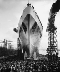 Crowds and cranes surrounding large ship at launch