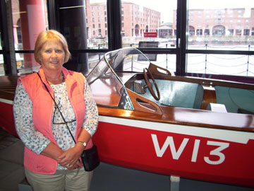 A visitor stood next to a red and white speedboat