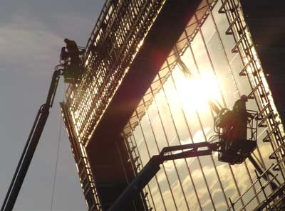 Sun on a large window and two men working on it