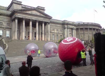 men rolling inflatable balls larger than they are in front of World Museum Liverpool